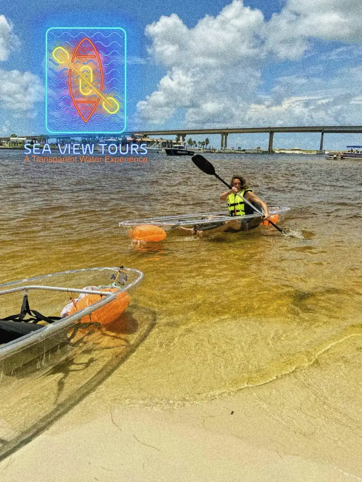 Clear kayaks with paddles and life jackets staged on the sand at Orange Beach
